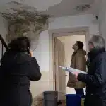 Dégât des eaux en copropriété : qui indemnise quand plusieurs appartements sont touchés ? Trois personnes inspectant plafond abîmé par infiltration