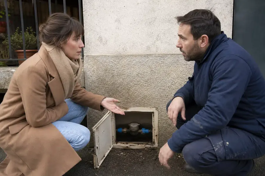 Une locataire et un plombier devant un compteur d’eau