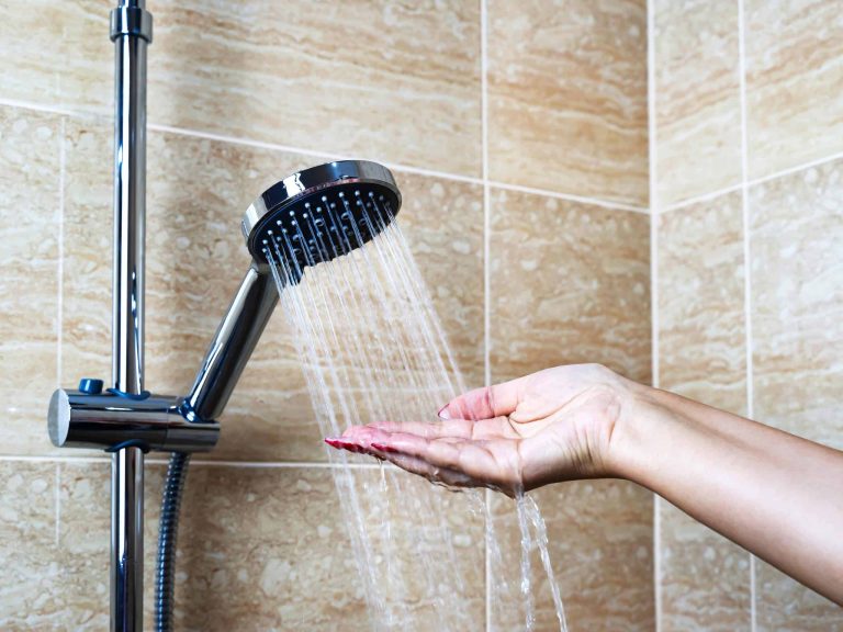 femme qui teste la température de l'eau de la douche